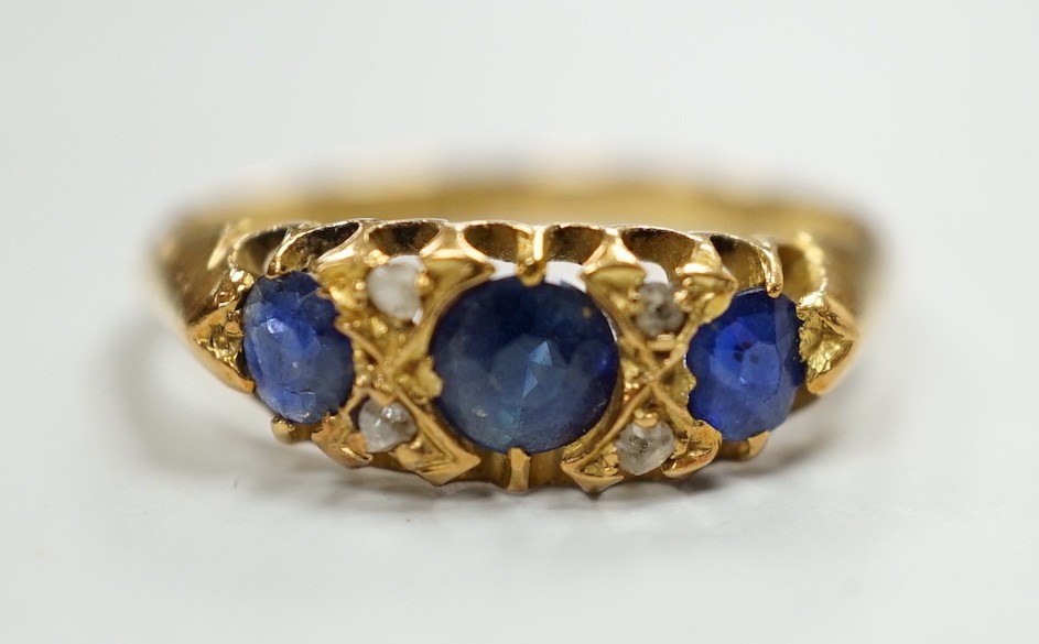 An Edwardian 18ct gold and graduated three stone sapphire set half hoop ring, with four stone rose cut diamond chip spacers, hallmarked for Birmingham, 1906, size P/Q, gross weight 3.2 grams.